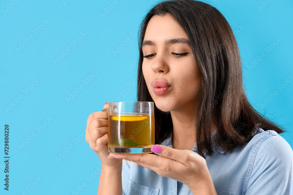 Young woman with glass cup of hot lemon tea on blue background, closeup Young woman with glass cup of hot lemon tea on blue background, closeup