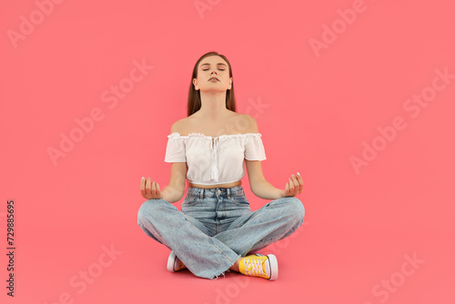 Attractive young girl sits on a pink background