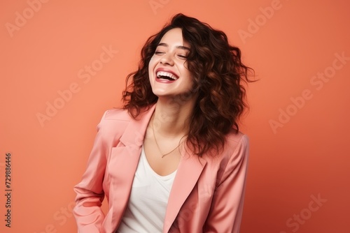 Portrait of a happy young woman laughing and looking up over orange background