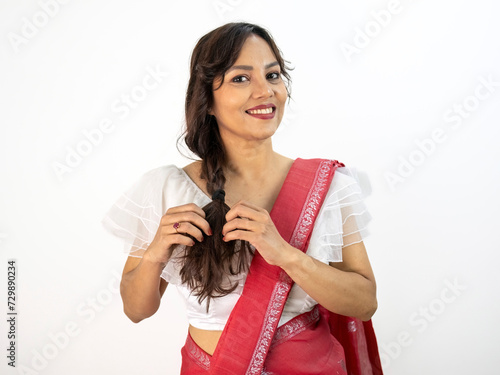 Elegant Indian woman posing in red sari or saree with intricate white border design and white blouse.