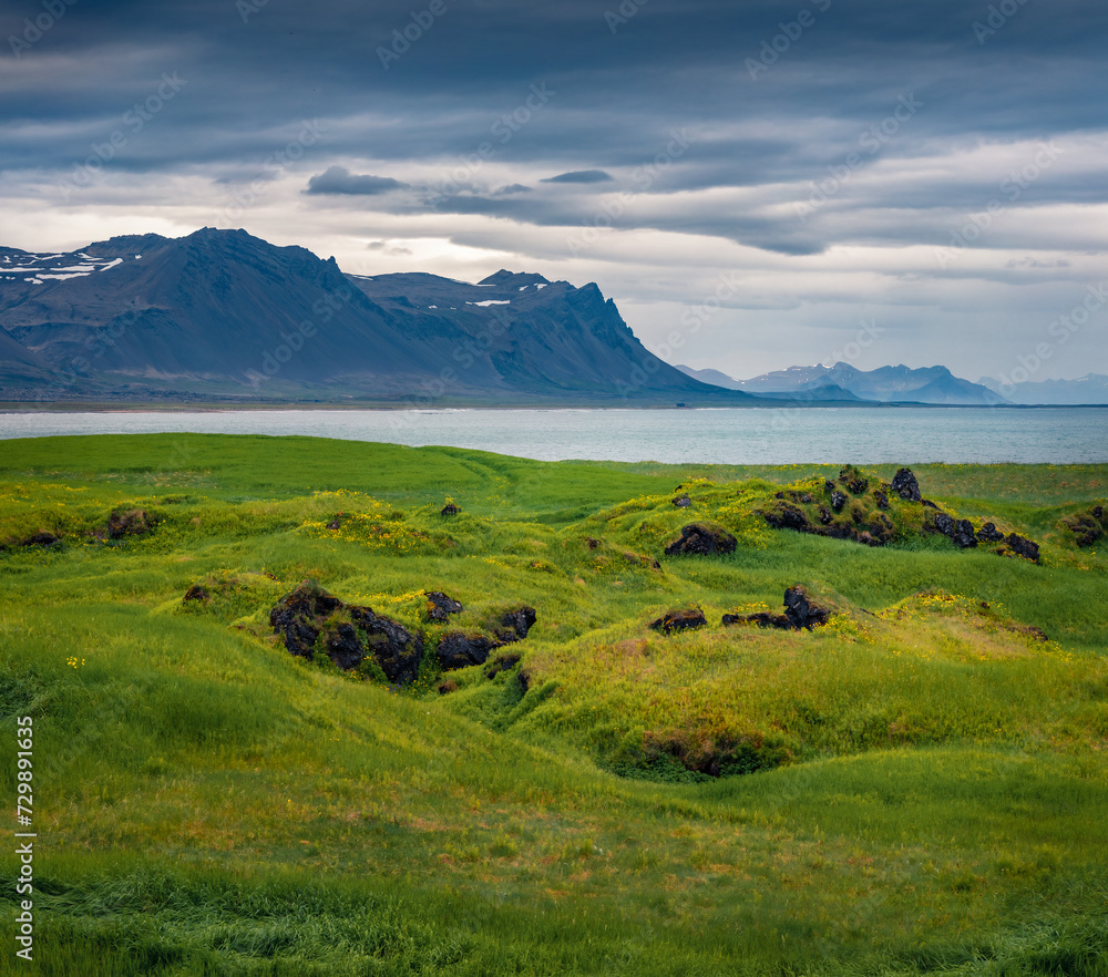 Gloomy summer view of valley among volcanic mountains. Green pasture near Budakirkja church at Snaefellsnes Peninsula, west coast of Iceland, Europe. Beauty of countryside concept background.