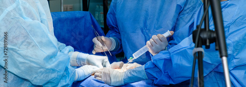 Hands of doctors and nurses in sterile gloves perform a surgical operation in the emergency department of a hospital. Surgeons operate with surgical instruments.