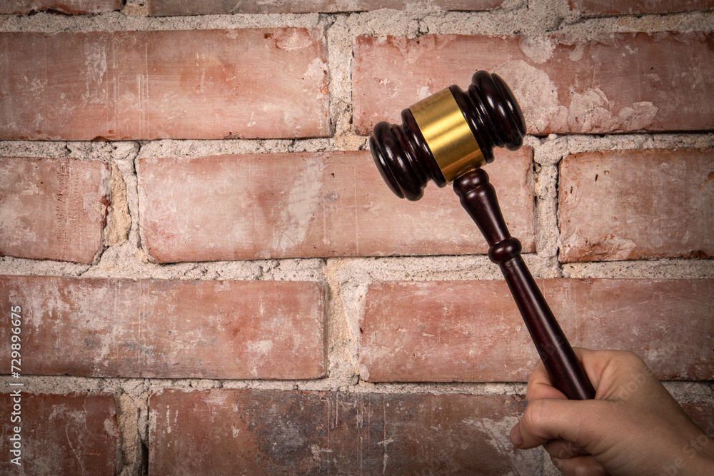 Judge hand holding gavel. Red brick background Judge hand holding gavel. Red brick background