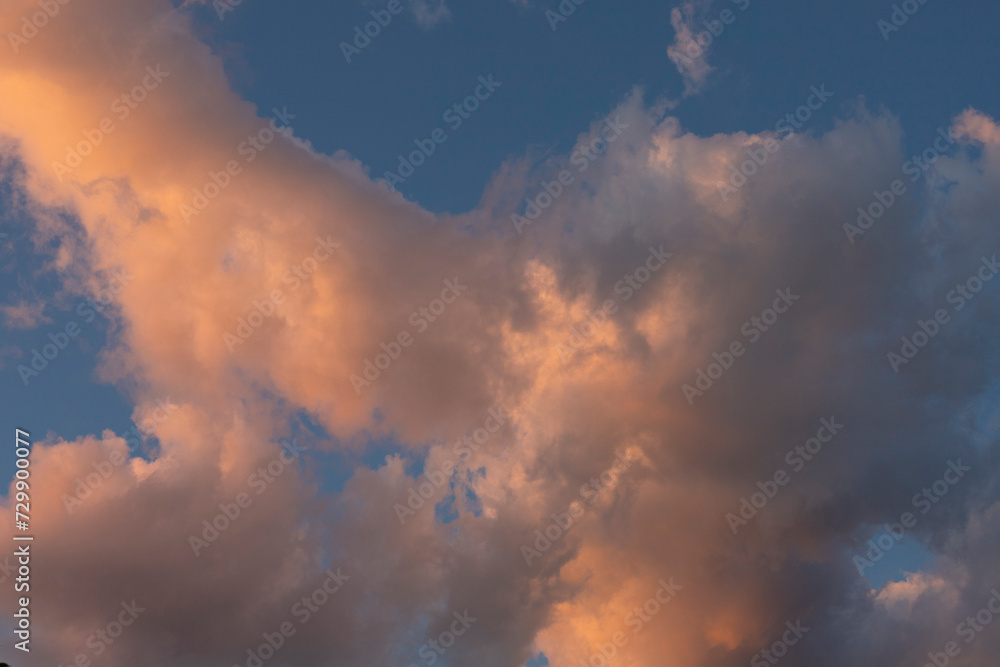 Cloud landscape. Pink and brown summer cumulus clouds on a blue sky during sunset. Wallpaper. Background.