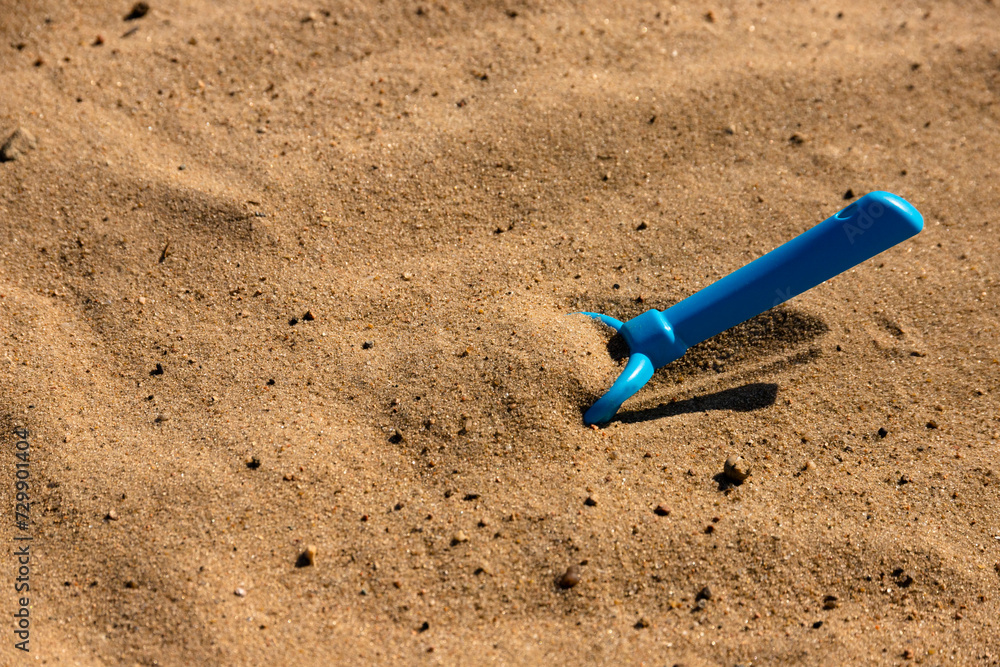 Children's sandbox, plastic toy children's shovel of blue color on a sandy beach by the sea. Children's psychedelic. selective focus. Children's sandbox, plastic toy children's shovel of blue color on a sandy beach by the sea. Children's psychedelic. selective focus.