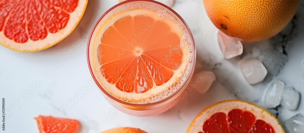 Top view of delicious grapefruit juice in glass with fresh fruit slices on white table. Top view of delicious grapefruit juice in glass with fresh fruit slices on white table.