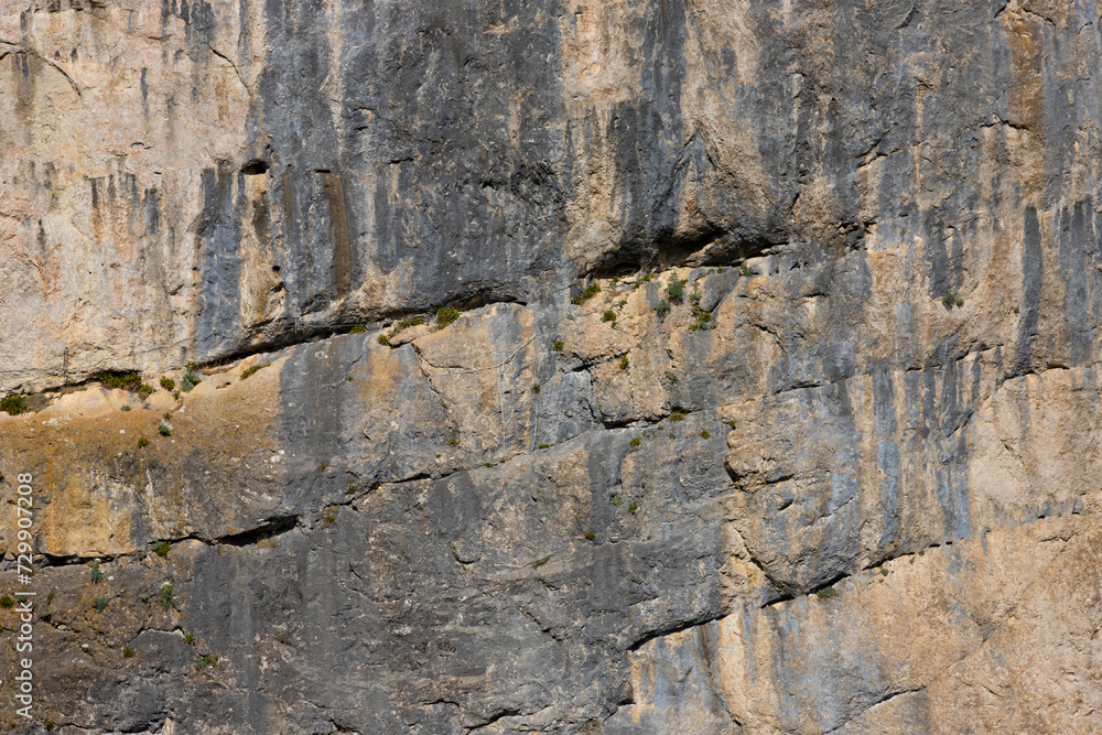 Fototapeta premium A sheer wall of red-gray color on a rock in the mountains, the texture of natural stone. Active sport. selective focus