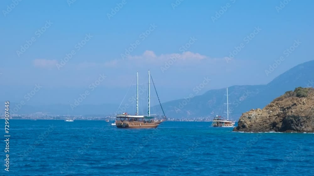 Wooden touristic yachts by stones island. A view of big wooden traveling ship sailing on waves in the sun rays. A concept of sea voyage and tropical paradise time. Wooden touristic yachts by stones island. A view of big wooden traveling ship sailing on waves in the sun rays. A concept of sea voyage and tropical paradise time.