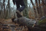 man stepping over a fallen log on the path
