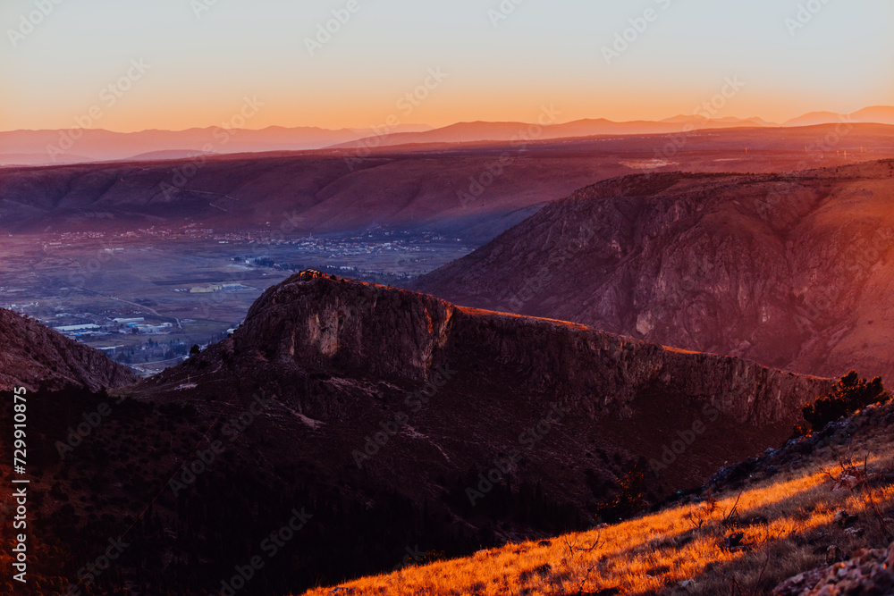 Obraz premium Capturing the breathtaking beauty of a vibrant orange and purple sunset over a majestic mountain during a serene summer evening