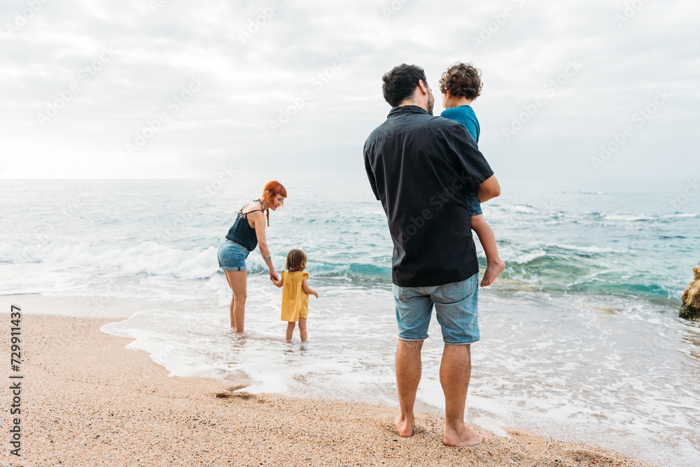 Family standing on seashore near waving seawater Family standing on seashore near waving seawater