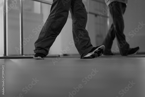 Low section of breakdancers legs dancing in studio. Blank and white tones