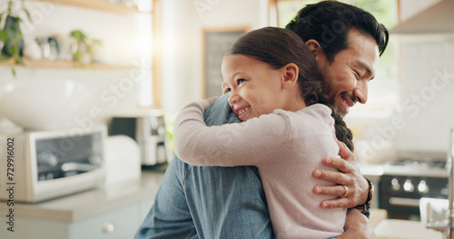 Family, father and daughter hug in the kitchen for love, trust or bonding together in their home. Kids, smile and safety with a happy young man embracing his adorable girl child in their house photo