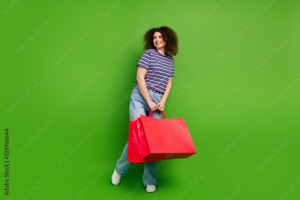 Full size portrait of nice lovely girl hold mall bags look empty space special sale offer isolated on green color background Full size portrait of nice lovely girl hold mall bags look empty space special sale offer isolated on green color background
