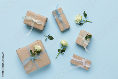 Gift boxes with beautiful white roses on blue background. International Women's Day