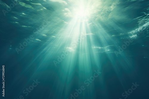The sun casts a shimmering glow as its rays penetrate the crystal-clear water of the ocean. © pham