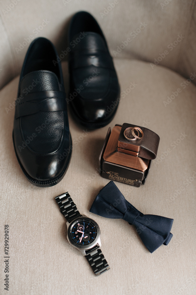 men's accessories of the groom black leather shoes, a watch, perfume and two wedding rings
