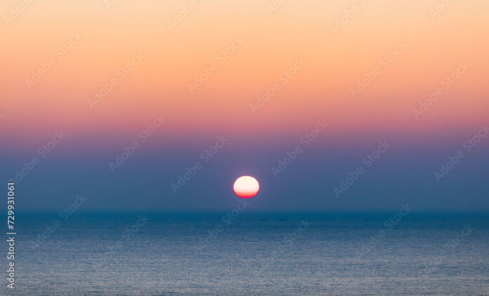 Sea sunrise landscape. Sunlight reflecting on the sea surface and a ship passing between it