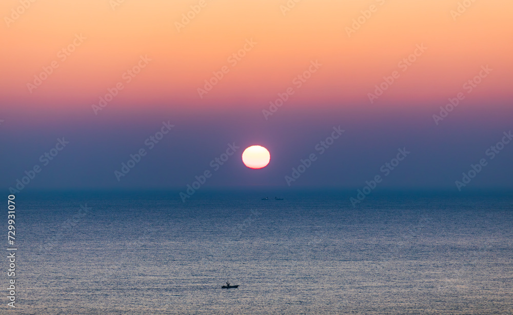 Sea sunrise landscape. Sunlight reflecting on the sea surface and a ship passing between it Sea sunrise landscape. Sunlight reflecting on the sea surface and a ship passing between it