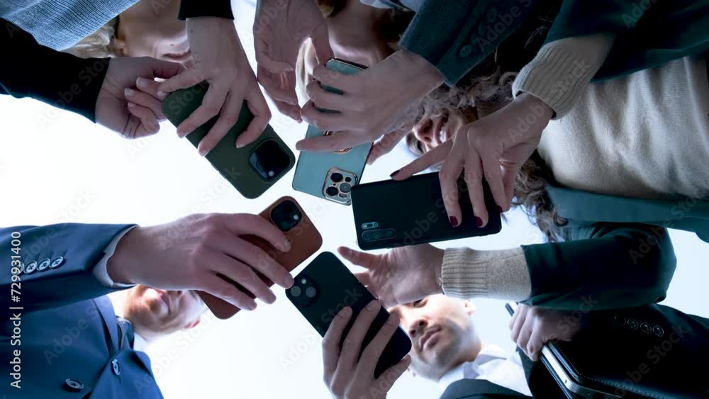 Low angle view of a group of busy international businesspeople using their smartphones at street. Low angle view of a group of busy international businesspeople using their smartphones at street.