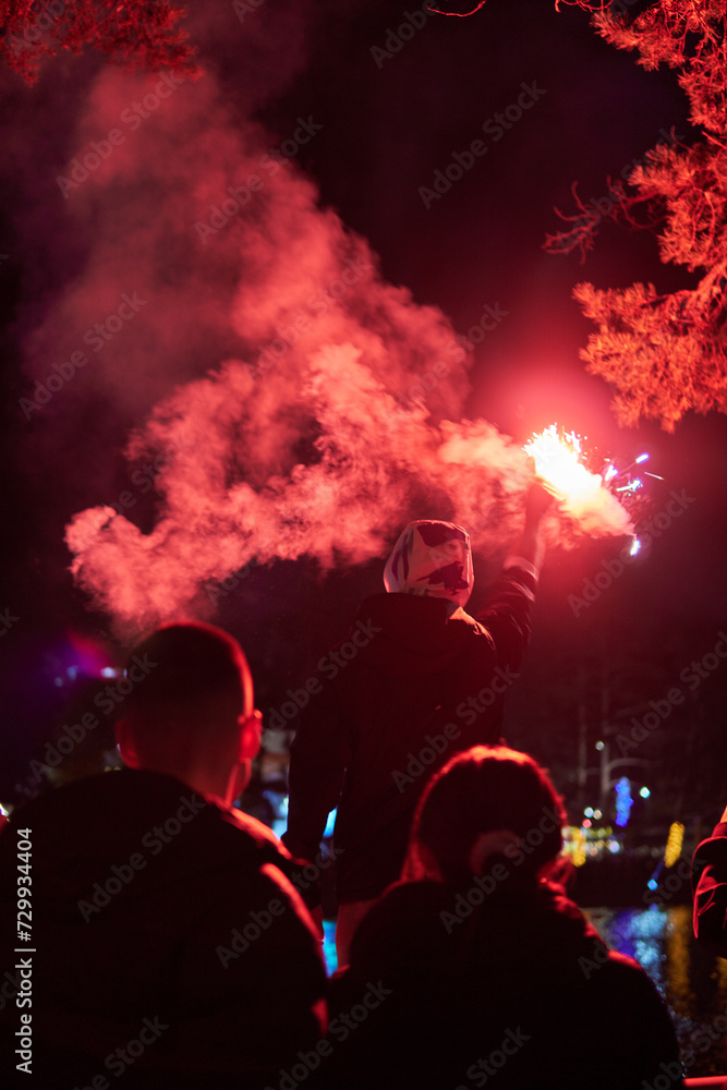 Fototapeta premium Man holding red torch with smoke to celebrate