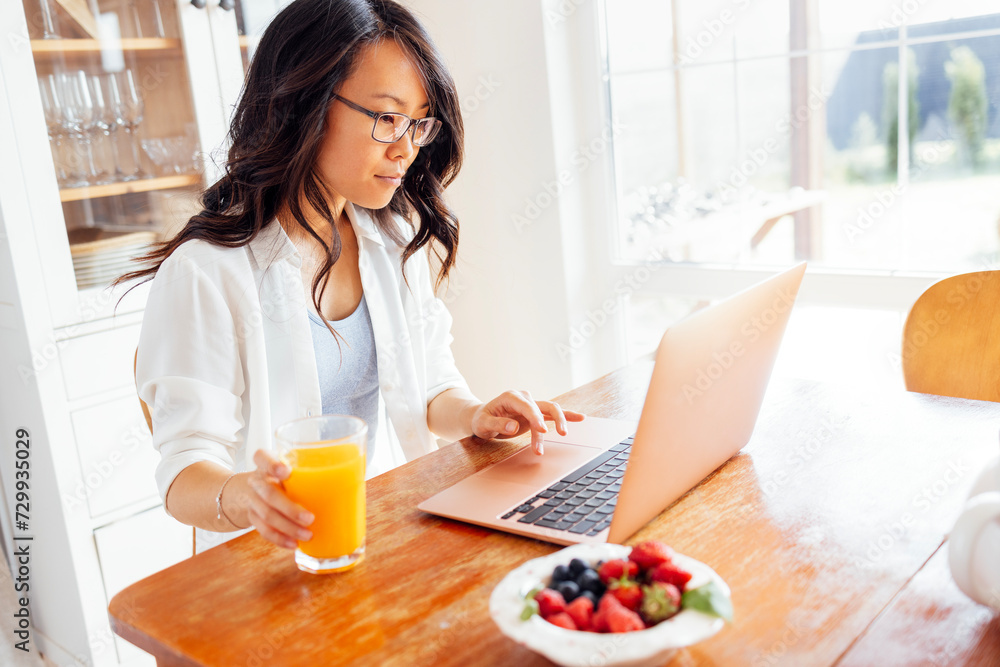 Lovely girl studies remotely in dining room at home.