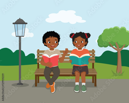 Cute African kids reading books discussing sitting on bench at the park 