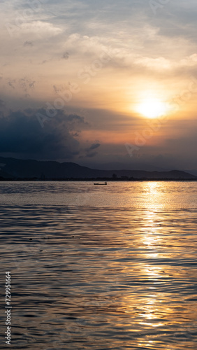 Silhouetted local fishermen in a traditional wooden fishing canoe boat against beautiful golden sunset reflecting over surface of ocean on tropical island of Timor-Leste in Southeast Asia