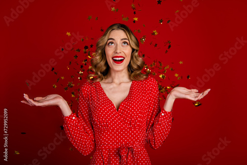 Portrait of positive astonished person raise arms open mouth flying star shape confetti isolated on vivid red color background