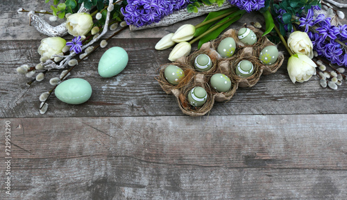 Flowers and Easter eggs on a wooden background with space for text.