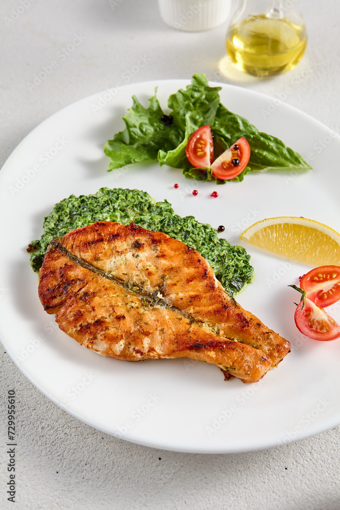 Pan-seared salmon steak with fresh spinach on white plate, perfect for healthy lifestyle and seafood cuisine presentations
