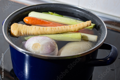 Pot with water and vegetables to make Christmas broth