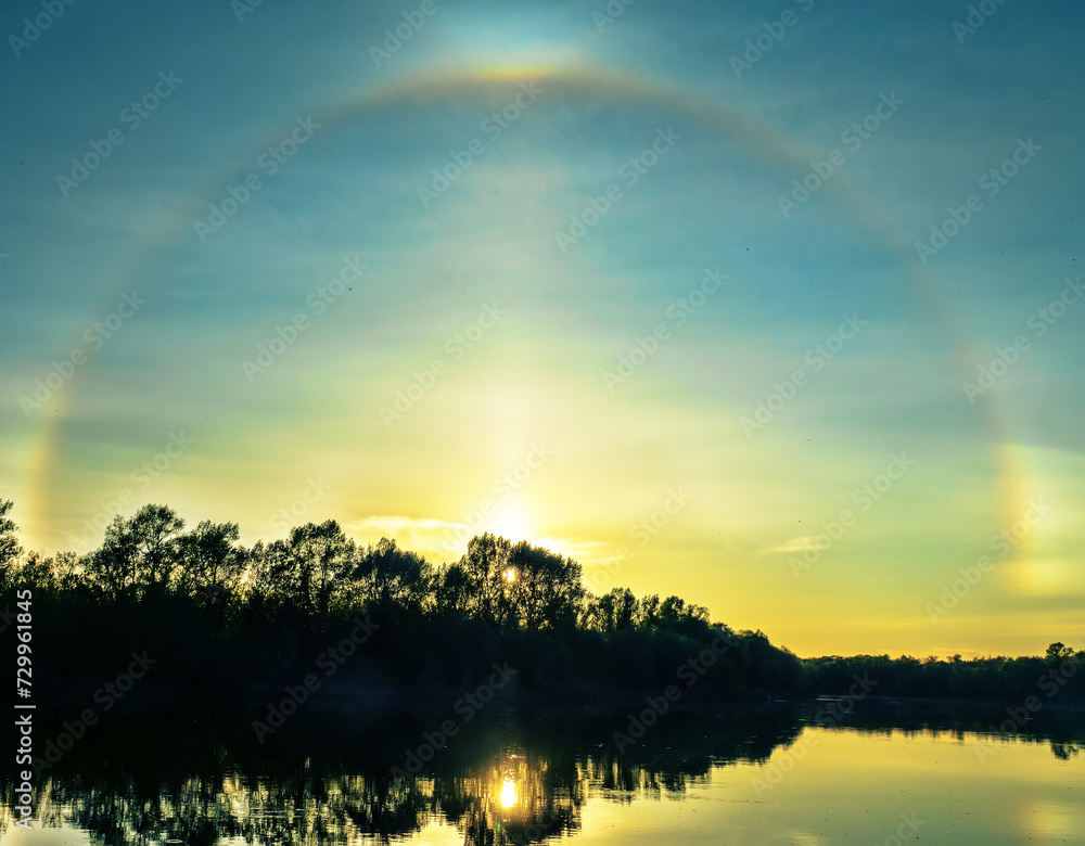 Unusual atmospheric phenomena. Very bright double halo (parhelic ring) over river at moment of evening sunset, windless spring day. Average flow of Don River. Mock sun with reflection in water