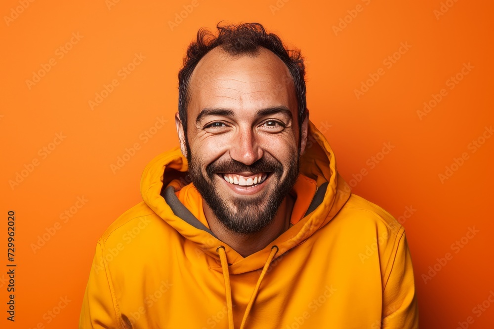 Portrait of a happy man in yellow hoodie on orange background Portrait of a happy man in yellow hoodie on orange background