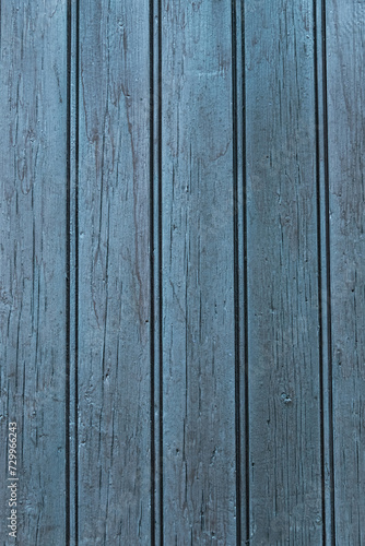 A vertical photograph of old boards painted with blue paint, which has worn out due to time and weather.