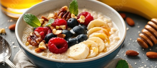 A bowl of oatmeal porridge with various fruits, nuts, and honey.