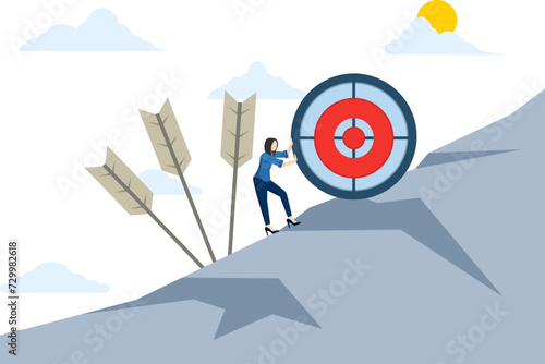 concept of difficulty in working hard to achieve a goal or setting a goal that is too high or unrealistic, missing the mark, businessman trying hard to push a dartboard or dart target up a hill.