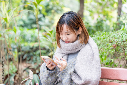 冬の寒い香港尖沙咀の公園で過ごす20代の中国人女性 A Chinese woman in her 20s spending time in a park in Tsim Sha Tsui, Hong Kong, which is cold in winter photo