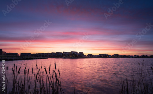 Modern suburb at the waterfront during a colorful sunrise in Meerstad, the Netherlands.