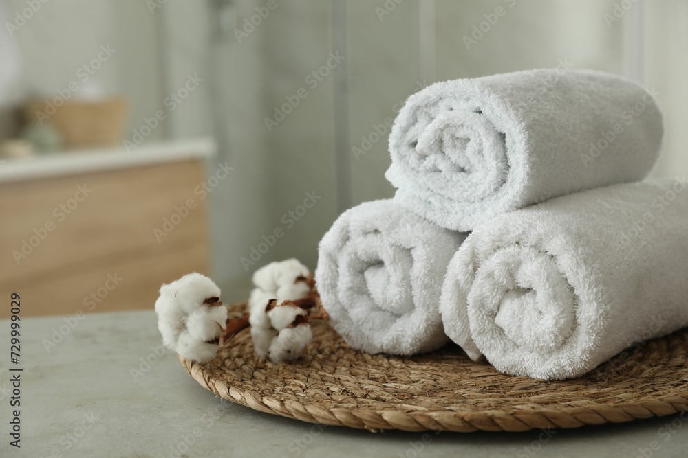 Clean rolled towels and cotton flowers on table in bathroom. Space for text Clean rolled towels and cotton flowers on table in bathroom. Space for text