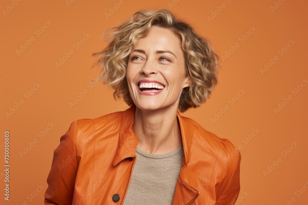 Portrait of happy middle-aged woman in orange jacket on orange background Portrait of happy middle-aged woman in orange jacket on orange background