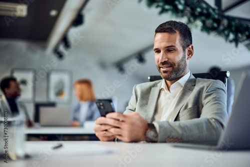 Businessman working at the co-working space, using a mobile phone. © bnenin