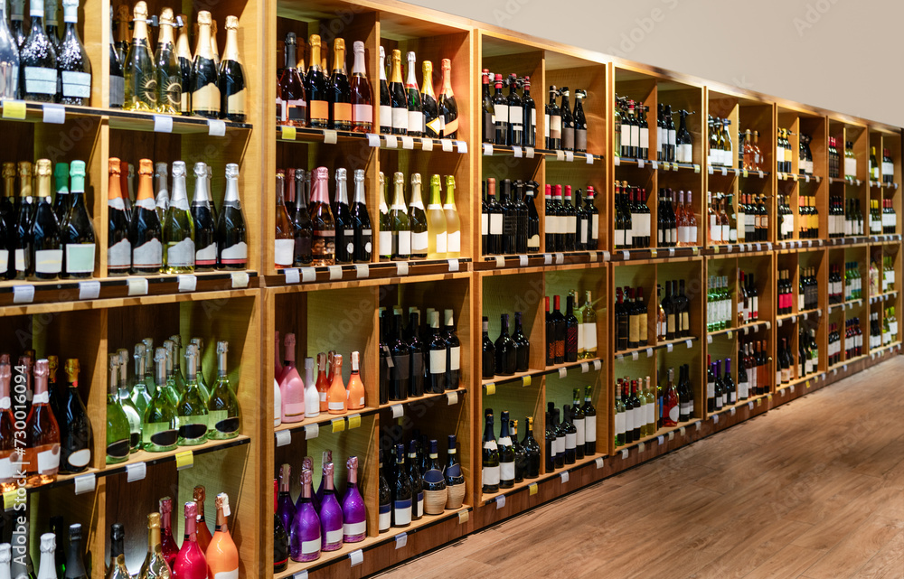 Big retail shelves with different wine bottles and selective focus. Banner for liquor store and wine production industry.