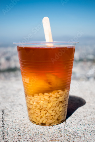 Mote con huesillo is a traditional Chilean summer beverage made with cooked husked wheat and dried peaches. Sweetened and flavored with caramelized sugar and cinnamon, it's a refreshing drink. photo