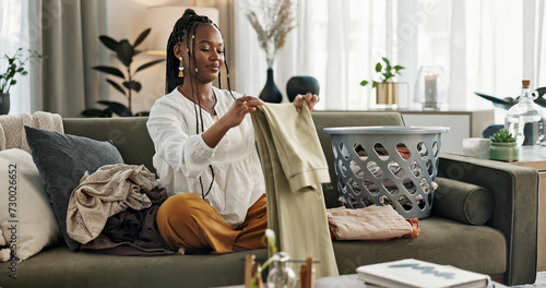 Fotografia Laundry, housework and a black woman folding washing on a sofa in the living room of her home to tidy
