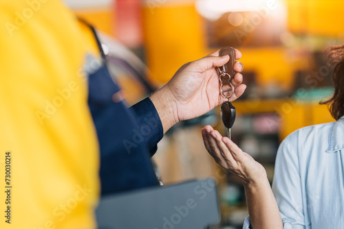 Mechanic car dealer giving car key to customer for finished car service fix problem or auto sell deal