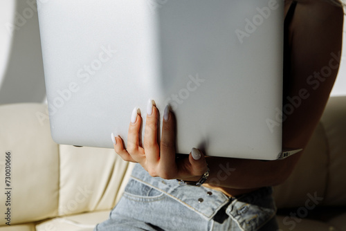 The girl is holding a laptop on a light background