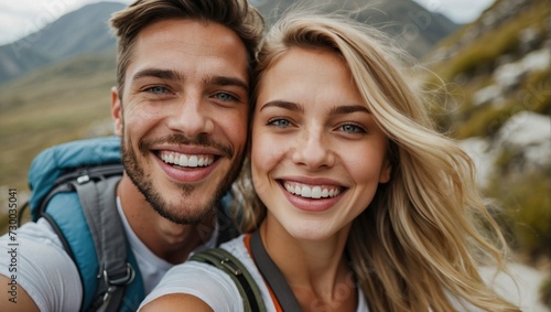 Close-up selfie of a cheerful young white couple with backpacks, smiling in the great outdoors, exuding warmth and happiness on their hiking adventure. photo