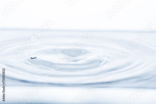 A tiny whirlpool on the water's surface amidst gentle waves against a pristine white backdrop. Ideal for illustrating tranquility and natural beauty.