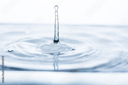 Vivid splash of a water droplet reflecting against a pristine white backdrop. Perfect for advertising, abstract art, or illustrating purity and freshness